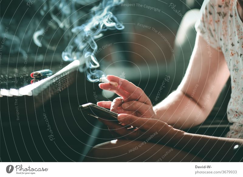 Frau mit Zigarette in der Hand tippt auf ihrem Handy herum Tippen Hände Finger rauchen Rauch Qualm Sucht Suchtverhalten suchtgefahr ungesund Alltagsleben Leben