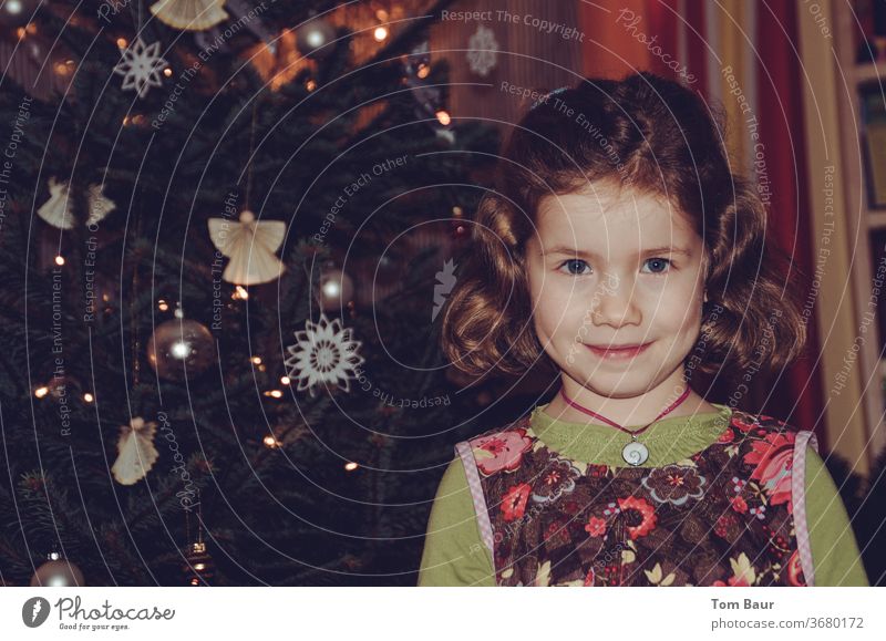 Portrait eines Mädchens vor dem Weihnachtsbaum weihnachtsbaum portät Engel christbaum blondes haar Blick in die Kamera fröhlich Fröhlichkeit festlich