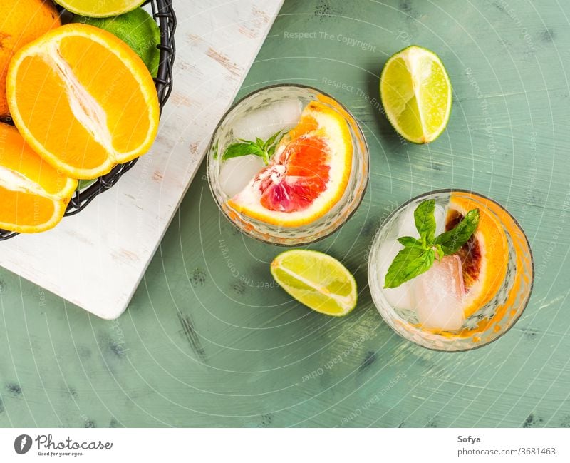 Frisches Sommer-Zitrusgetränk mit Eis auf Grün trinken Zitrusfrüchte Wasser Cocktail Limonade Entzug Mocktail Blutorange Frucht flache Verlegung Draufsicht Kalk