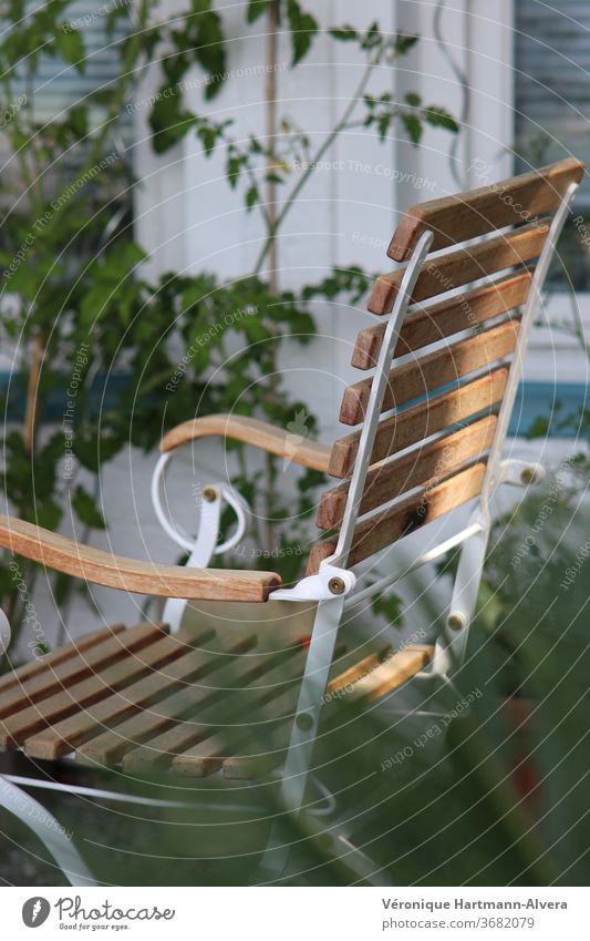 Gartenstuhl aus Holz und Metall mit Tomatenpflanze an Hauswand Stuhl Farbfoto ruhig Möbel Gartenmöbel Ruhepunkt Entspannung im Garten Pause Außenaufnahme