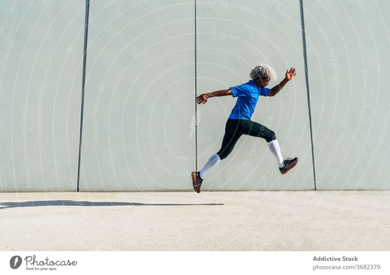 Afroamerikanischer Sportler, der auf die Straße springt Sprung Training Fitness Gebäude Wand Großstadt Energie modern männlich Athlet schwarz ethnisch