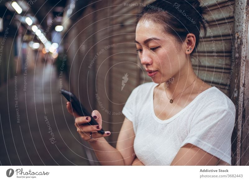Ethnische Frau mit Smartphone zu Fuß auf U-Bahn-Gang Durchgang unterirdisch Spaziergang Großstadt Fußgänger Öffentlich schließen urban Fensterladen Gewerbe jung