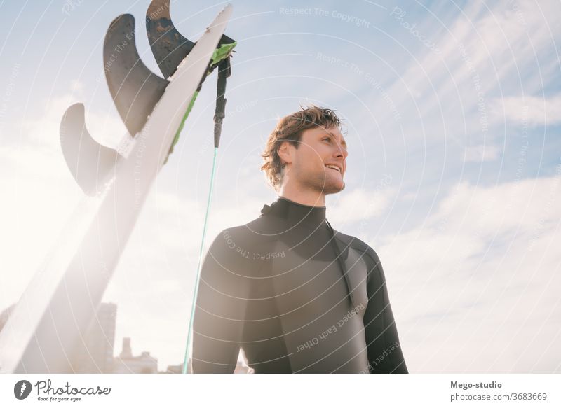 Surfer, der am Strand neben seinem Surfbrett steht. Mann Brandung Wasser Sport Surfen MEER Meer im Freien sportlich Küstenlinie Wellen Hintergrund Abenteuer