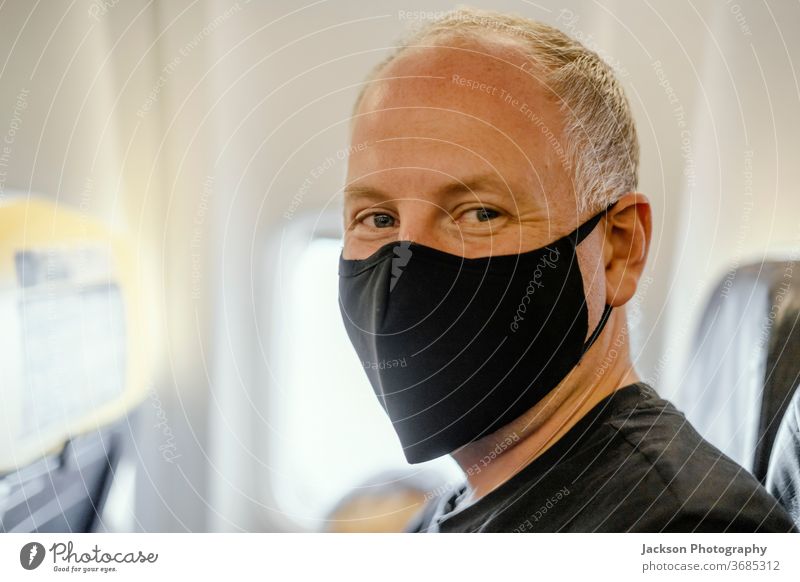Im Flugzeug sitzender Mann mit schützender Gesichtsmaske Mundschutz Ebene Reisender Prävention Krankheit Menschen Virus Coronavirus covid-19 Glück positiv