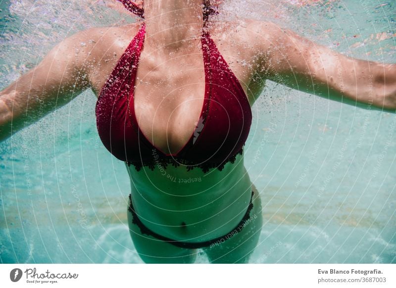 Nahaufnahme einer jungen Frau, die in einem Schwimmbad unter Wasser taucht. Sommer und lustiger Lebensstil abschließen Schwimmsport Blasen Spaß Kaukasier Pool