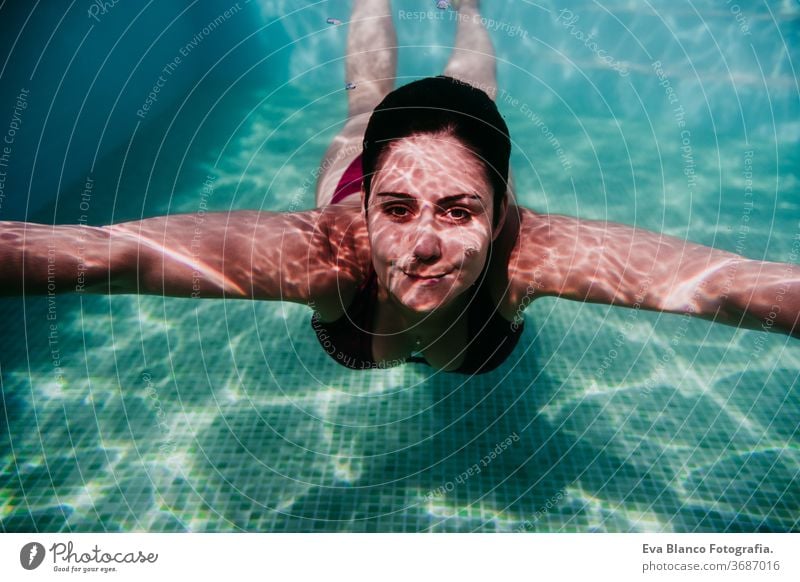 junge Frau, die in einem Schwimmbad unter Wasser taucht. Sommer und lustiger Lebensstil Schwimmsport Blasen Spaß Kaukasier Pool Sinkflug Lifestyle übersichtlich
