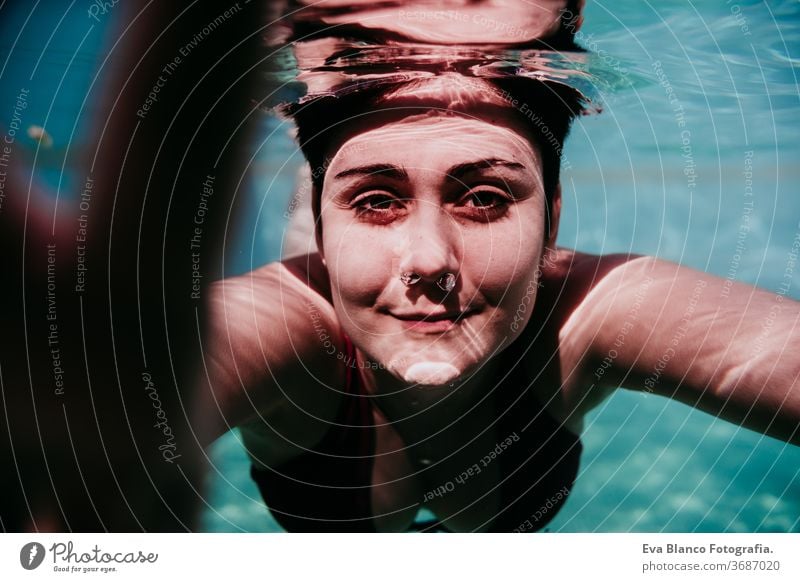 Porträt einer jungen Frau, die in einem Schwimmbad unter Wasser taucht. Sommer und lustiger Lebensstil berührend Hand Schwimmsport Blasen Spaß Kaukasier Pool