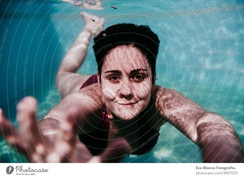 Porträt einer jungen Frau, die in einem Schwimmbad unter Wasser taucht. Sommer und lustiger Lebensstil abschließen Schwimmsport Blasen Spaß Kaukasier Pool