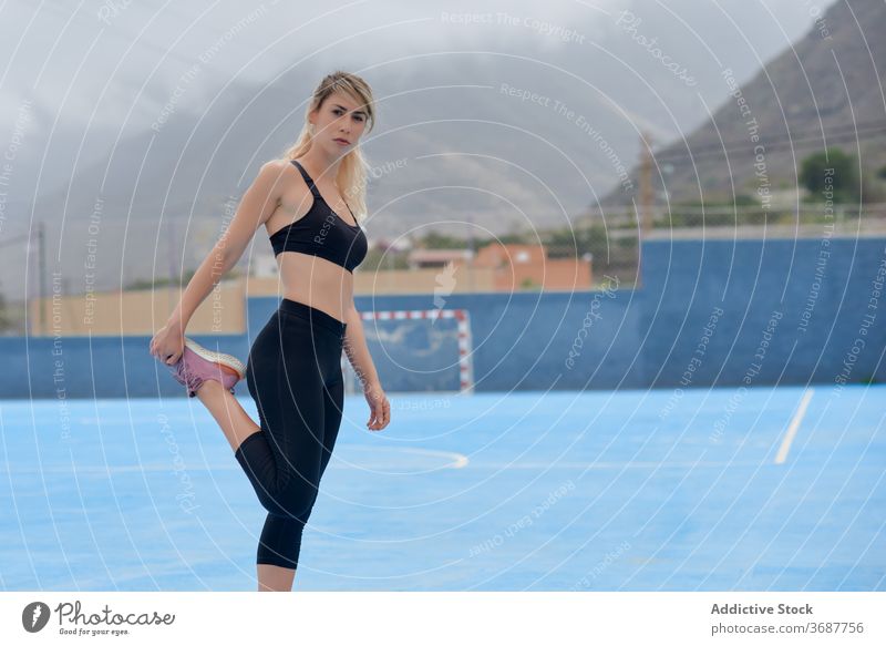 Schlanke Sportlerin streckt die Beine auf dem Sportplatz Frau Training Übung Dehnung Fitness Athlet Läufer schlank jung modern Wellness Wohlbefinden Gesundheit