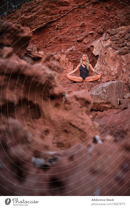 Frau in einem Badeanzug sitzt in der Meditation in einem trockenen Terrain quer vertikal bleiben Ruinen Gelände Oberfläche vereinzelt Verlassen Yoga Natur