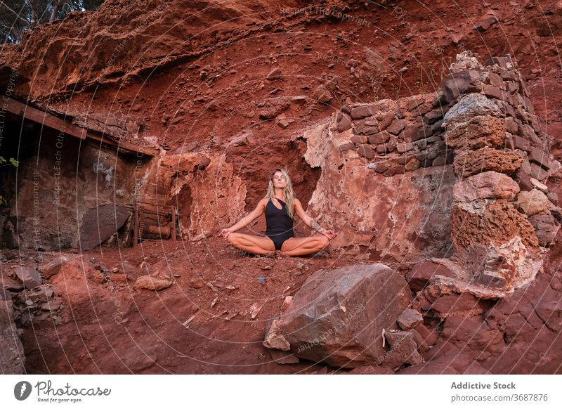 Frau in einem Badeanzug sitzt in der Meditation in den Ruinen eines Hauses in einem trockenen Terrain antik bleiben Gelände Oberfläche vereinzelt Verlassen Yoga