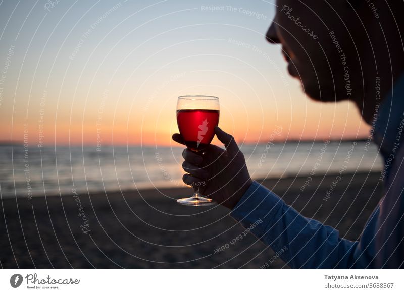 Mann mit einem Glas Wein am Strand bei Sonnenuntergang trinken Alkohol romantisch genießend langsames Leben sich[Akk] entspannen MEER schön Feier Getränk