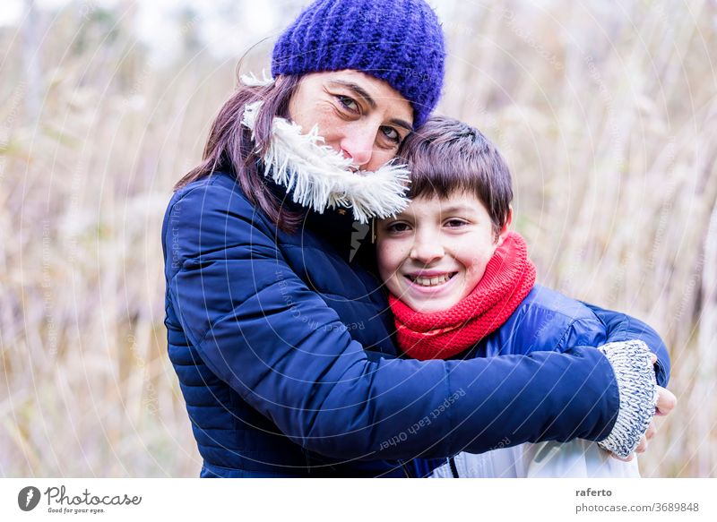 Mutter mit Wollmütze umarmt Sohn mit Liebe im Freien 2 Kaukasier jung Lächeln Menschen Umarmung Frau Familie heiter schön Senior Lifestyle reif Porträt Glück