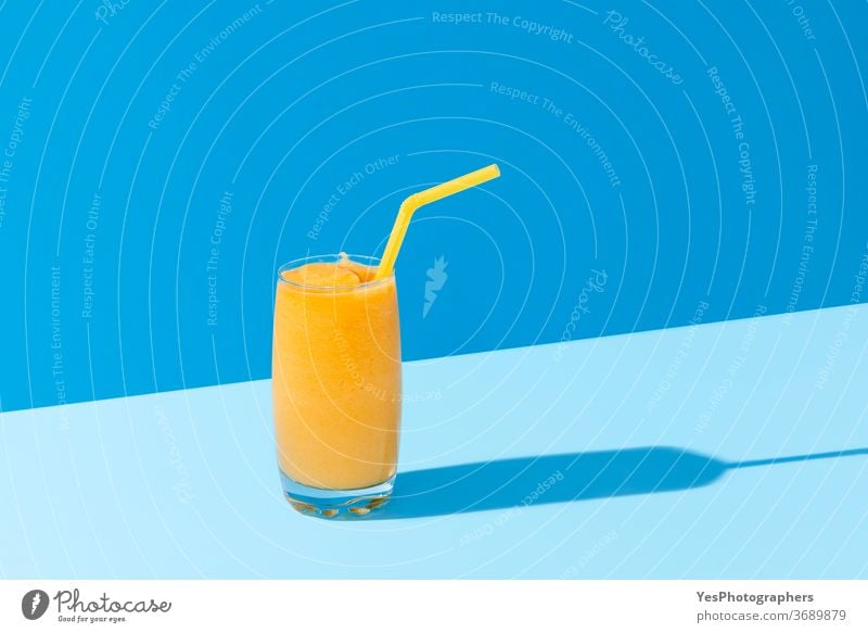 Mango-Smoothie auf blauer Farbe. Sommerliches Getränk. Mangoshake mit Strohhalm Hintergrund hell Cocktail kalt Farben Textfreiraum ausschneiden lecker Dessert