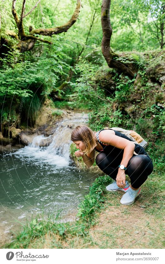 Junge weibliche Naturforscherin trinkt Wasser aus der Quelle aktiv Aktivität Erwachsener Abenteuer Rucksack Backpacker Bach trinken Ökologie erkunden Entdecker