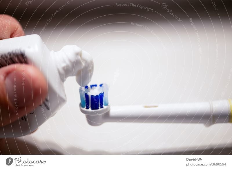 Zahnpasta für die Zahnbürste Zahn der Zeit Zahnarzt Zahnpflege Zahnmedizin Finger Hand drücken Zahncreme Textfreiraum oben Starke Tiefenschärfe