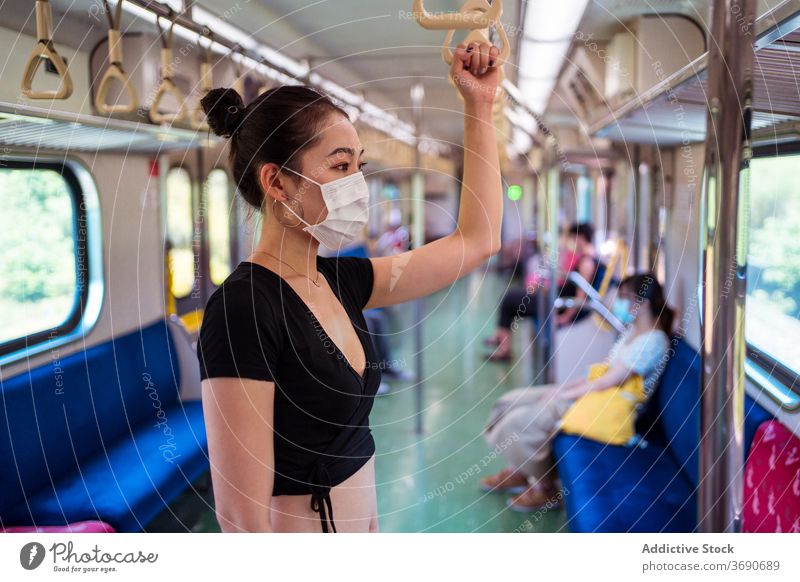 Asiatische Frau in Maske im Zug reisen Mundschutz Coronavirus Öffentlich Verkehr Ausbruch behüten Arbeitsweg ethnisch asiatisch modern Passagier stehen Ausflug