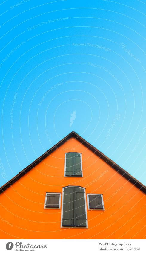Orangefarbenes Haus gegen blauen Himmel. Haus mit orangefarbenen Wänden minimalistisch. Deutsche Architektur Deutschland abstrakt Antiquität Dachboden