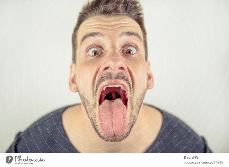 Mann schaut mit offenem Mund crazy in die Kamera weit geöffnet Zunge verrückt Profil Gesicht durchgeknallt Porträt Mund geöffnet lecken zunge zeigen