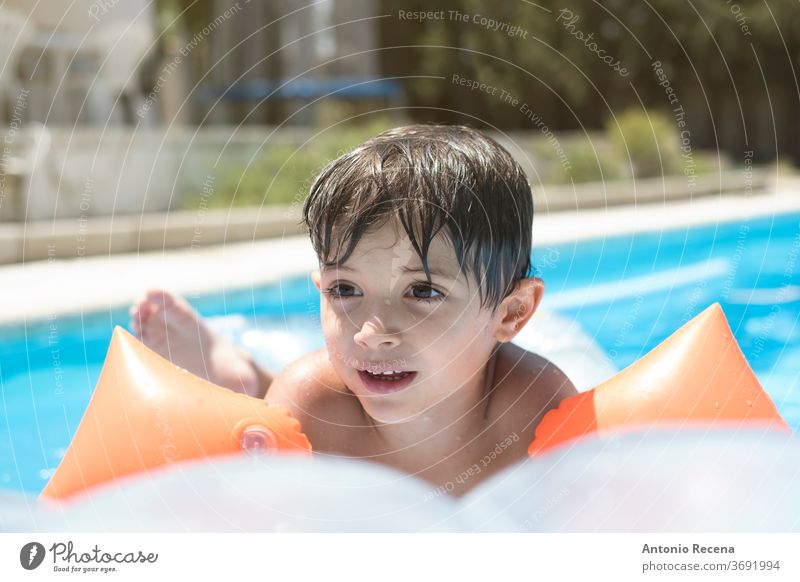 Kleinkind mit Muffen und schwimmt auf einer Matte in einem Schwimmbad oberirdisches Schwimmbecken vor Hinterhof Junge Windstille Kaukasier Kind Kindheit