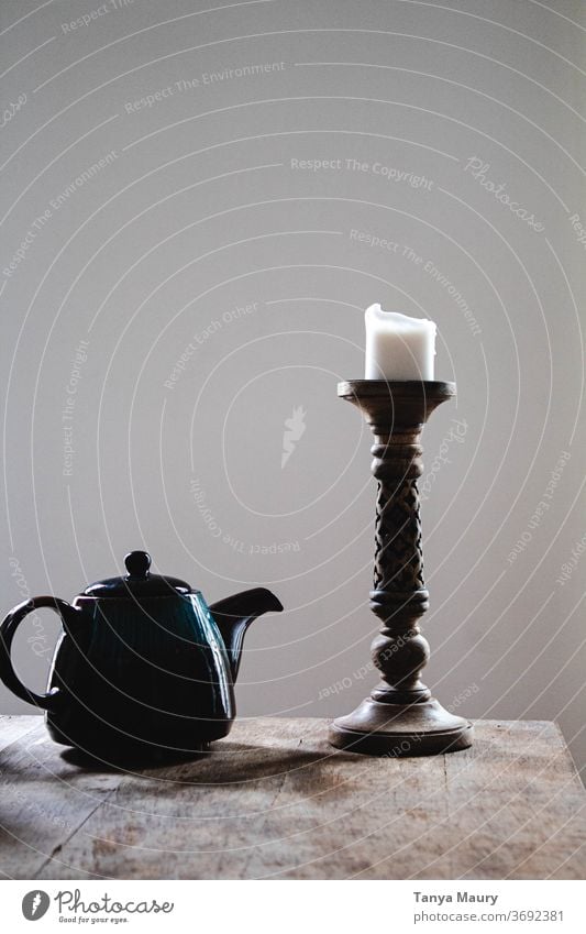 Blaue Teekanne und weiße Kerze auf einem Holztisch mit gräulichem Hintergrund Leuchter Innenaufnahme Beleuchtung Licht Dekoration & Verzierung grau
