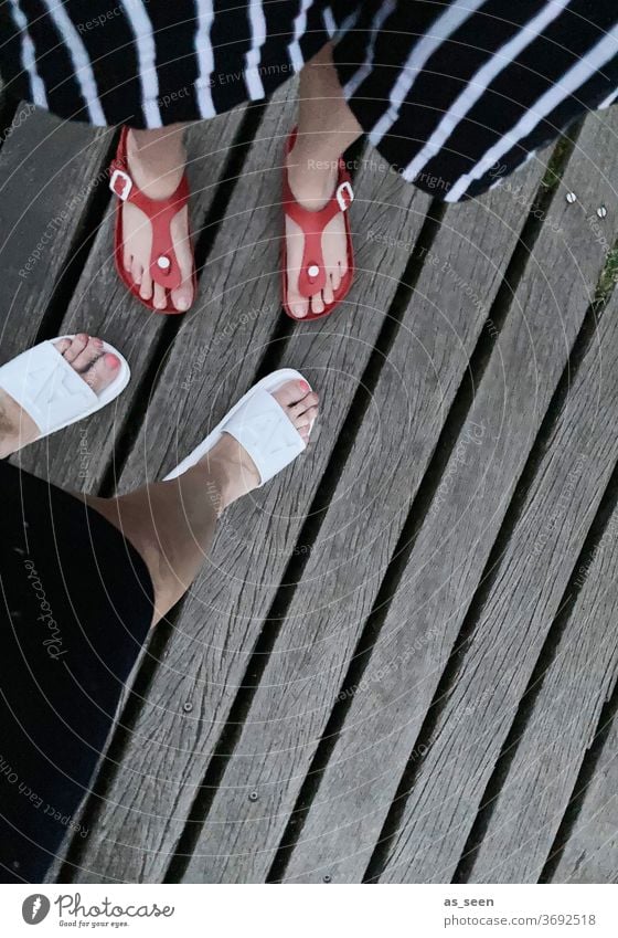 Füße am Steg von oben Schuhe Badeschuhe Sandalen Beine Holz Holzsteg Frau 2 Damenschuhe weiblich Außenaufnahme gesztreift Hose rot weiß grau Streifen Baden See
