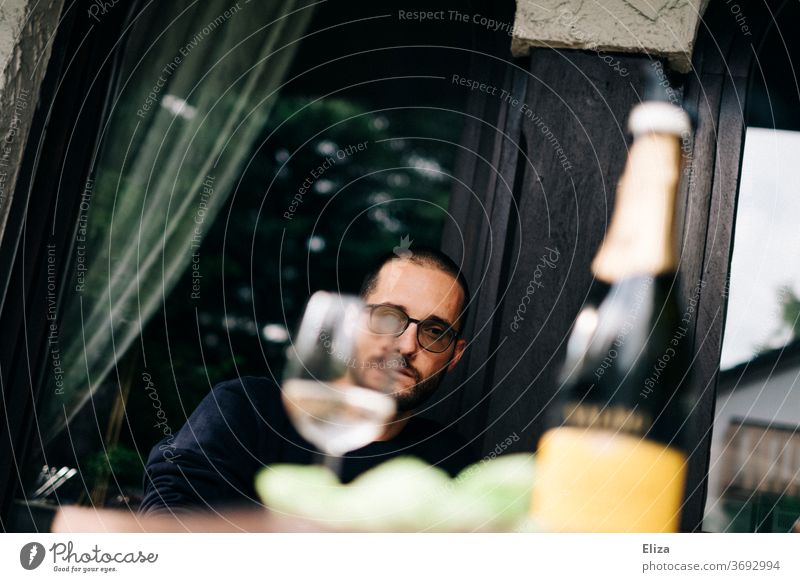 Das Gesicht eines Mannes hinter einem gefüllten Weinglas versteckt trinken grimmig Glas Alkohol Getränk Party Flasche Sektflasche Prosecco Restaurant draußen