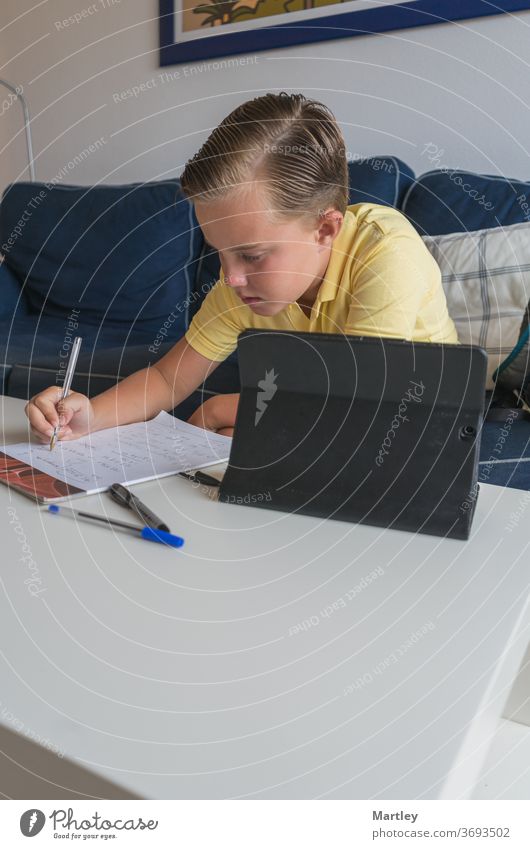 Kleiner Junge online mit seinen Klassenkameraden während einer Videokonferenzschaltung, macht seine Arbeit auf einem Notebook und teilt seine Mathearbeit mit ihnen.