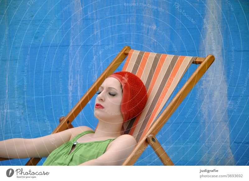 Das Mädchen mit der schönen roten Badekappe und grünem Badeanzug nimmt im Liegestuhl ein Sonnenbad. Eine Sommerliebe. Frau Badebekleidung Badehaube Haut jung