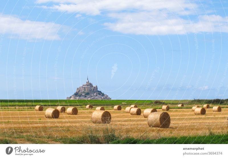 Strohrollen auf einem Feld, im Hintergrund Mont St. Michel Frankreich Bretagne Sommer Sonne Strohballen Getreideernte blauer Himmel gelb grün Wolkenhimmel