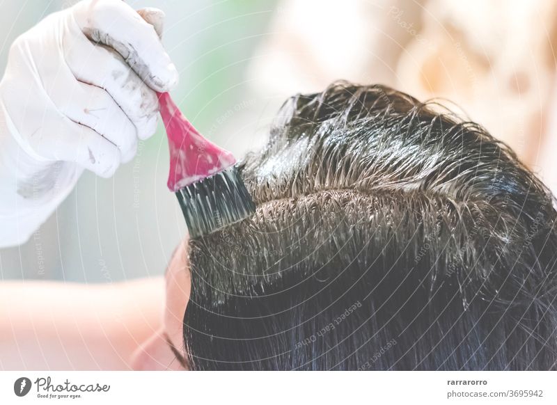 eine junge brünette, kaukasische Frau, die sich zu Hause mit einer rosa Bürste und weißen Handschuhen die Haare färbt Behaarung Schönheit Farbstoff Farbe