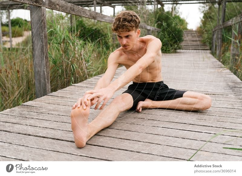 Shirtless Mann macht Yoga auf der Terrasse padmasana üben beweglich Natur Windstille männlich Pose Harmonie Konzentration Zen Asana hölzern Gesundheit