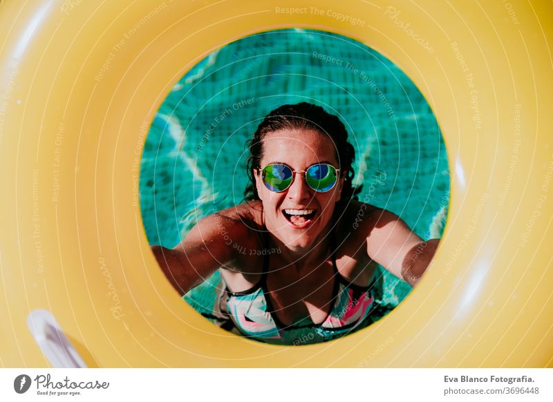 Draufsicht einer glücklichen jungen Frau in einem Pool mit einem gelben Donut in der Hand. Sommer und lustiger Lebensstil gelbe Donuts aufblasbar Schwimmsport