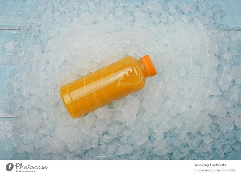 Flasche mit frischem Orangensaft über zerstoßenem Eis orange Saft eine Kunststoff Haustier satt gequetscht gepresst zerdrückt Hintergrund Nahaufnahme blau weiß