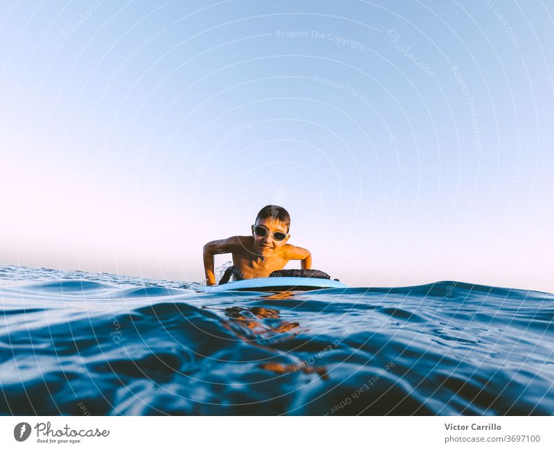 Ein kleiner Junge lernt an einem sonnigen Sommertag draußen an der Küste im Bodyboard bodyboarder Kind Feiertag Urlaub Freizeit Ufer Lifestyle Surfbrett