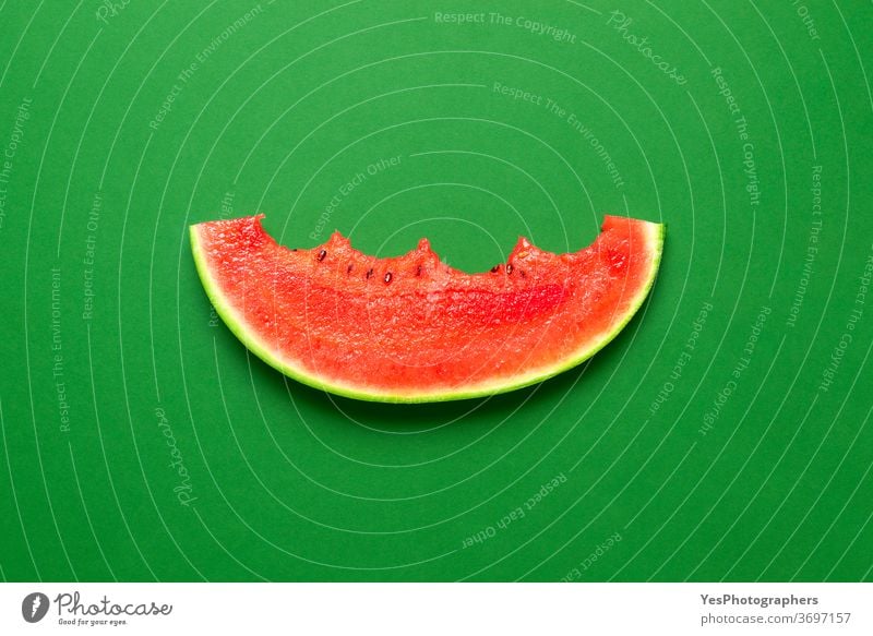 Isolierte Wassermelonenscheibe auf grünem Hintergrund. Gebissene Wassermelonenscheibe in der Draufsicht. obere Ansicht gebissen farbig farbenfroh geschnitten