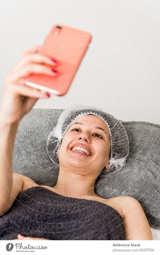 Glückliche Frau nimmt Selfie nach Schönheitsbehandlung Kosmetologie Smartphone zufrieden Klient Gesichtsbehandlung Hautpflege jung Foto genießen Mobile Telefon