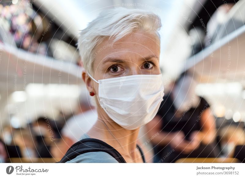 Im Flugzeug stehende Frau mit Gesichtsmaske Mundschutz reisen Reisender Gang Innenbereich Lifestyle post-covid-19 Corona-Virus sicher neue Normale Ausbruch
