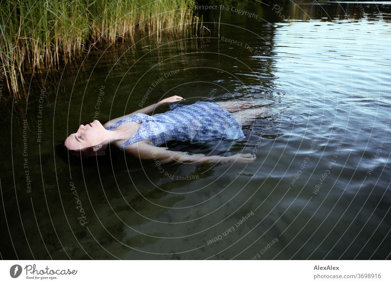 Portrait einer Frau die in einem See treibt vor einem Ufer mit Schilf zart Licht sportlich feminin Empathie Gefühle emotional Blick in die Kamera Porträt