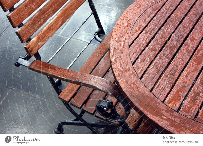 Im Regen stehen gelassen Tisch Stuhl Holz Möbel Sitzgelegenheit Stuhllehne Holzstuhl braun nass Regentropfen Gartenmöbel Biergarten außengastronomie Terrasse