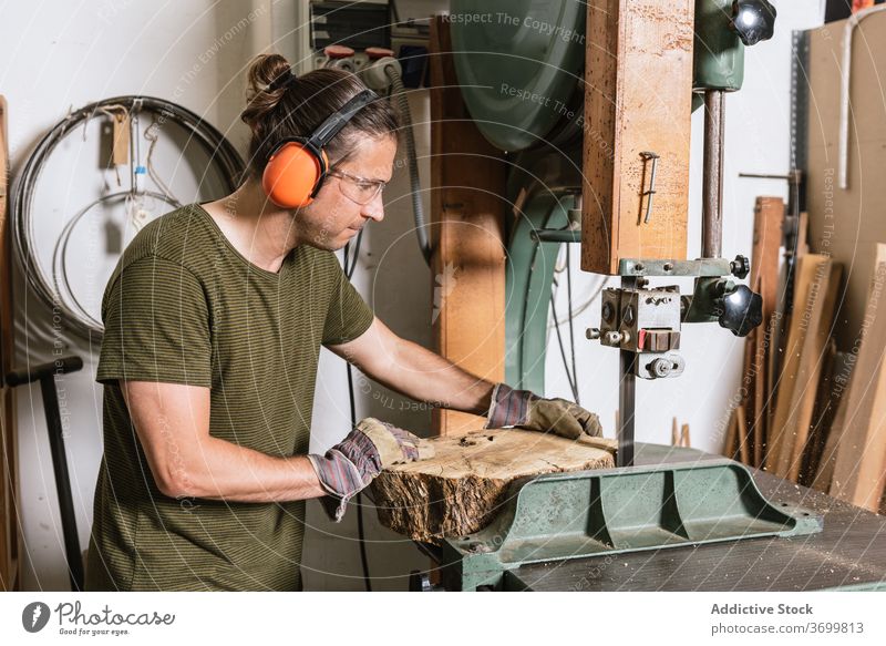 Männlicher Holzarbeiter schneidet Holz in der Werkstatt geschnitten Bandsäge Zimmerer Mann Tischlerin Holzarbeiten professionell männlich Nutzholz Säge schäbig
