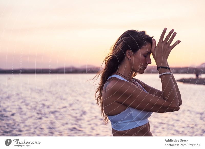 Fokussierte Frau meditiert in der Nähe von Fluss meditieren See Sonnenuntergang Yoga Harmonie Zen Natur Mudra friedlich üben Pose Gleichgewicht Windstille ruhig