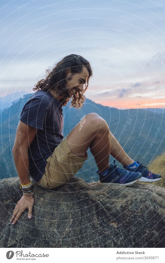Mann sitzt auf dem Rand eines Bergfelsens und bewundert die Aussicht Reisender Berge u. Gebirge Sonnenuntergang heiter bewundern Landschaft erstaunlich Glück