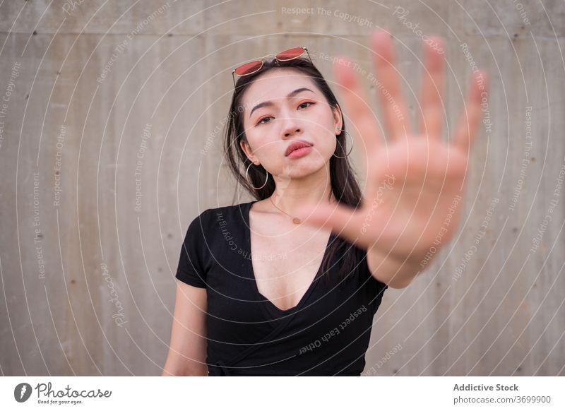 Ethnische Frau zeigt Stopp-Geste auf der Straße stoppen Zeichen gestikulieren zeigen verweigern manifestieren Symbol urban Stil ethnisch asiatisch Großstadt