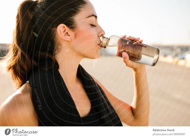 Junge sportliche Frau mit Getränkeflasche auf der Straße trinken ruhen passen Augen geschlossen positiv aktiv Training stehen Erfrischung Energie jung Flasche