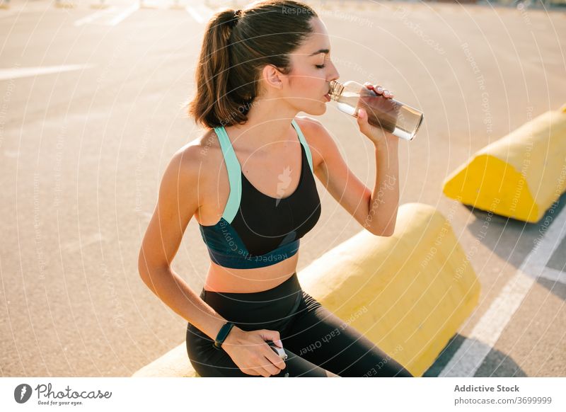Junge sportliche Frau mit Getränkeflasche auf der Straße trinken ruhen passen Augen geschlossen positiv aktiv Training Erfrischung Energie jung Flasche