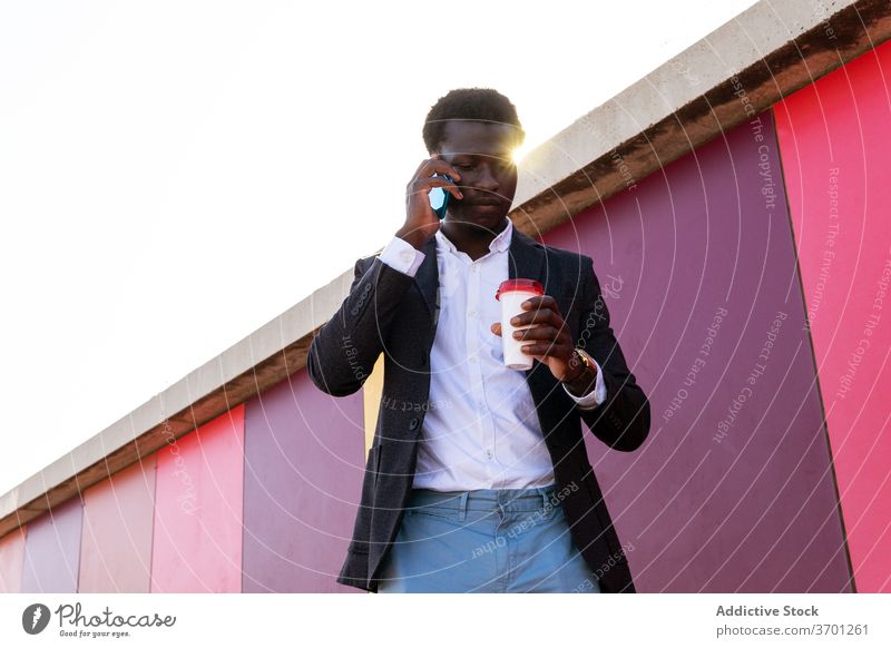 Stilvolle Geschäftsmann mit Kaffee sprechen auf Smartphone auf der Straße reden urban Imbissbude ernst diskutieren Anruf Mann jung Afroamerikaner schwarz