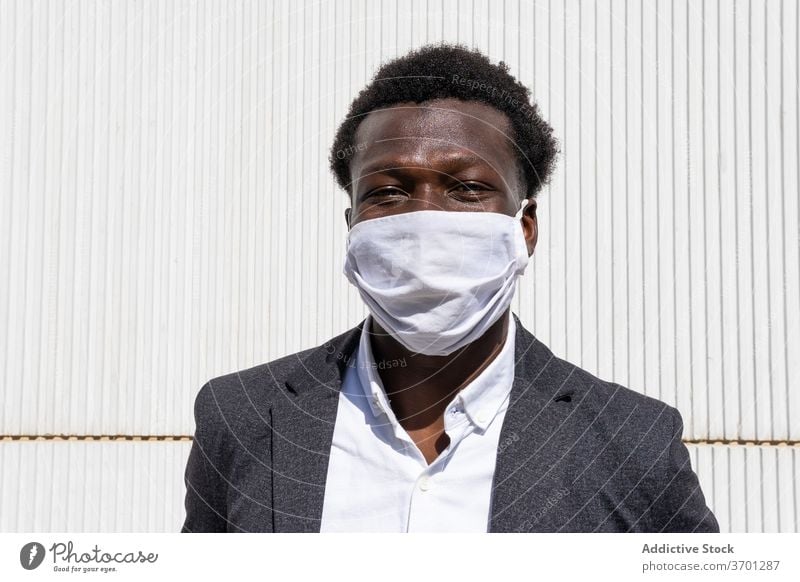 Fröhlicher schwarzer Geschäftsmann mit Schutzmaske Mundschutz behüten Coronavirus Pandemie COVID heiter Unternehmer formal Porträt Mann positiv Straße jung