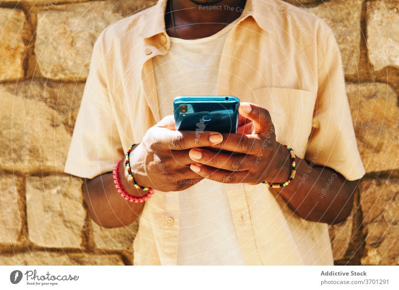 Anonymer ethnischer Mann mit Smartphone Talkrunde soziale Netzwerke unterhalten Wochenende benutzend Nachricht Großstadt männlich schwarz Afroamerikaner