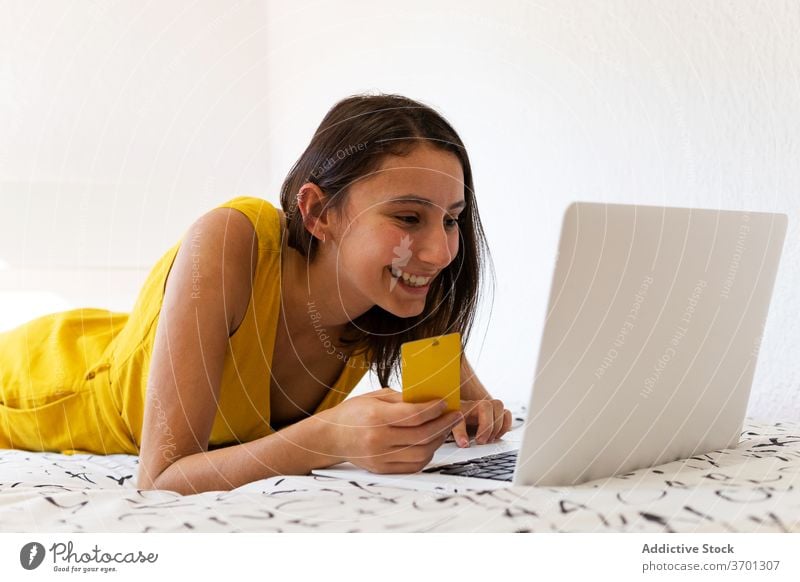 Lächelnde Frau beim Online-Kauf mit Kreditkarte Werkstatt online Zahlung Plastikkarte benutzend Laptop Internet verbrauchen konsumgeil Konsumverhalten